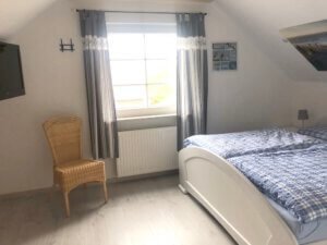 Schlafzimmer mit weißem Bett und Stuhl