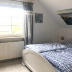 Schlafzimmer mit weißem Bett und blauen Vorhängen