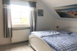 Schlafzimmer mit weißem Bett und blauen Vorhängen